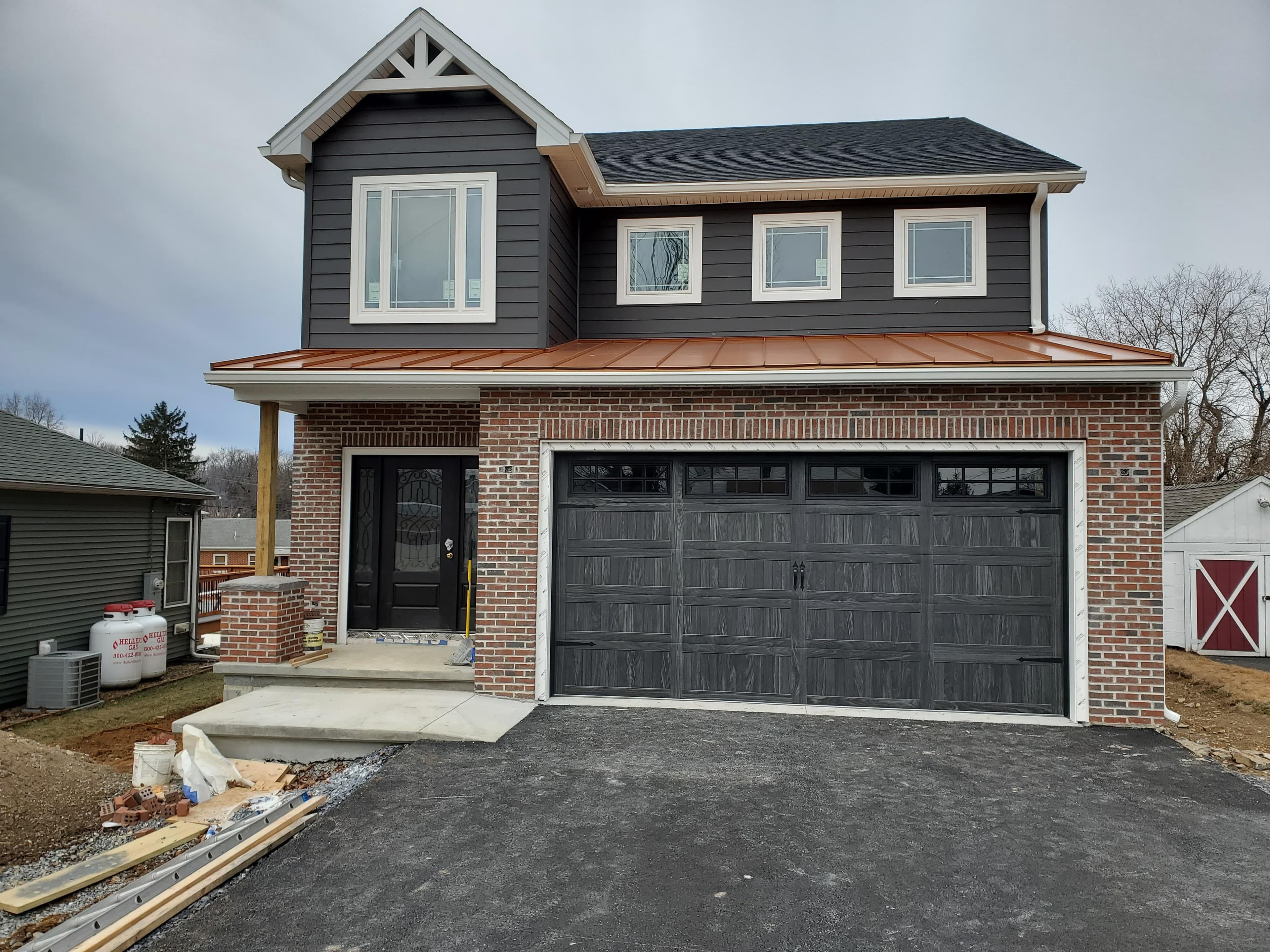 Dark raised-panel double garage door on a brick and siding home